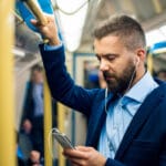 Serious businessman travelling to work. Standing inside undergro