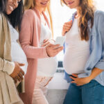 multicultural smiling pregnant women using smartphone